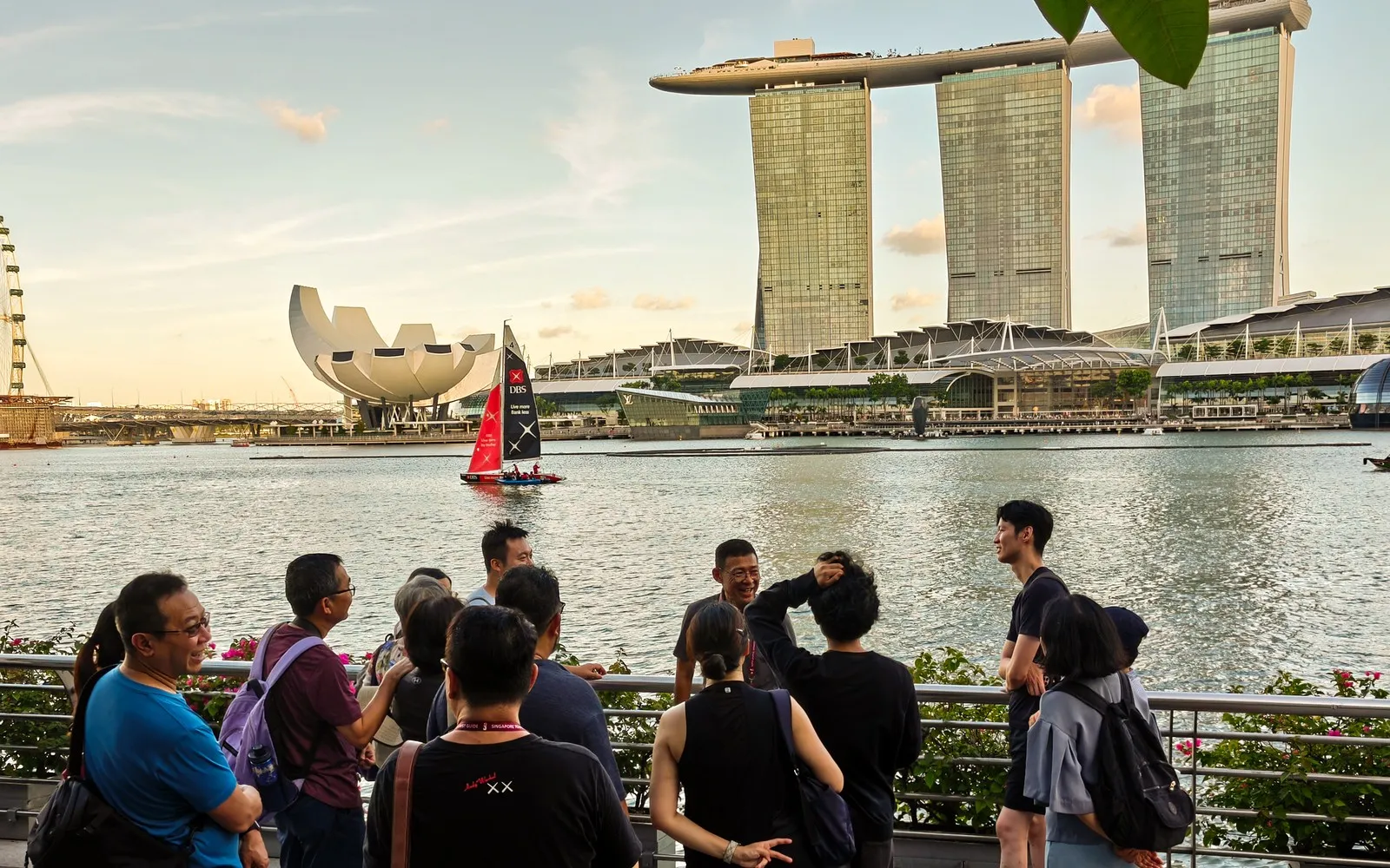 Guided group walking tour along the Singapore River with the city skyline behind them